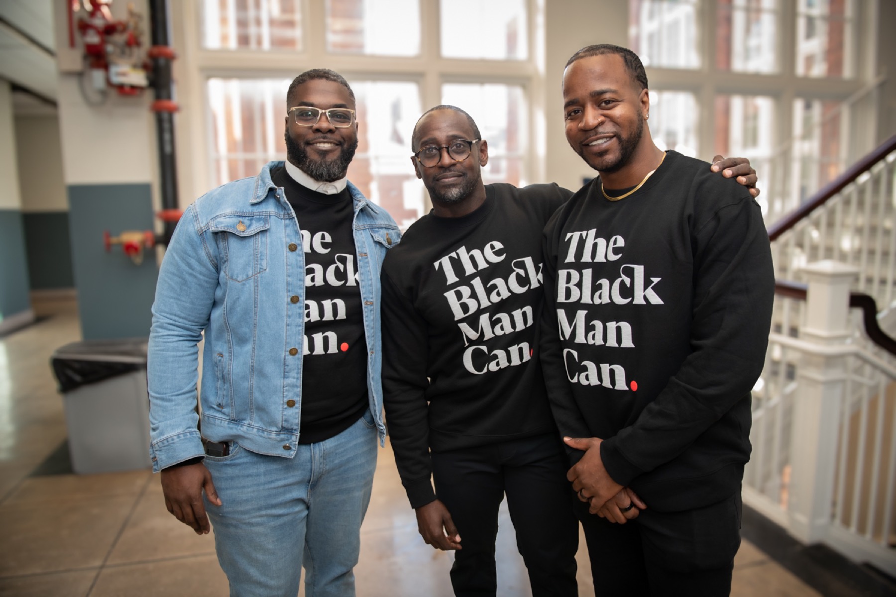 Three educators in The Black Man Can shirts smiling together